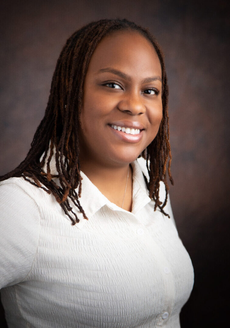 A woman with dreads is smiling for the camera.